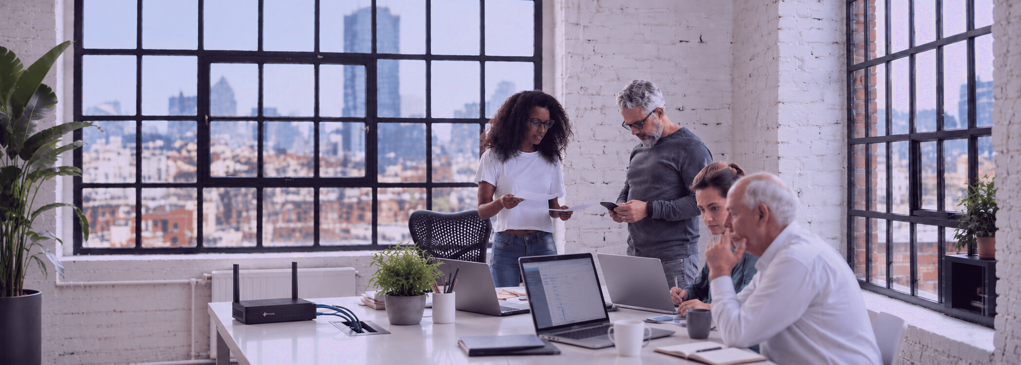 A small business team working in a loft office, laptops on the table and the business broadband router beside them