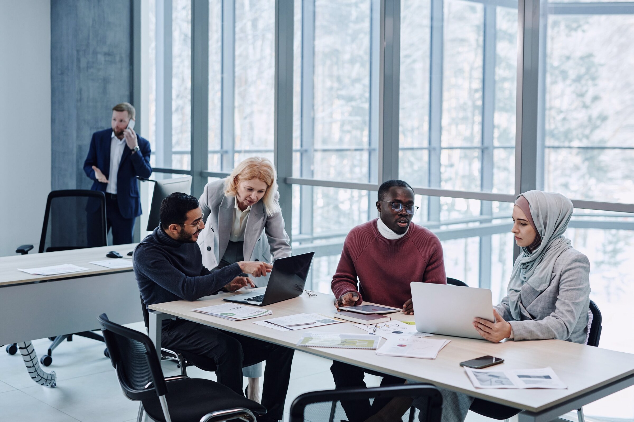 A team working on laptops around a table in a bright office