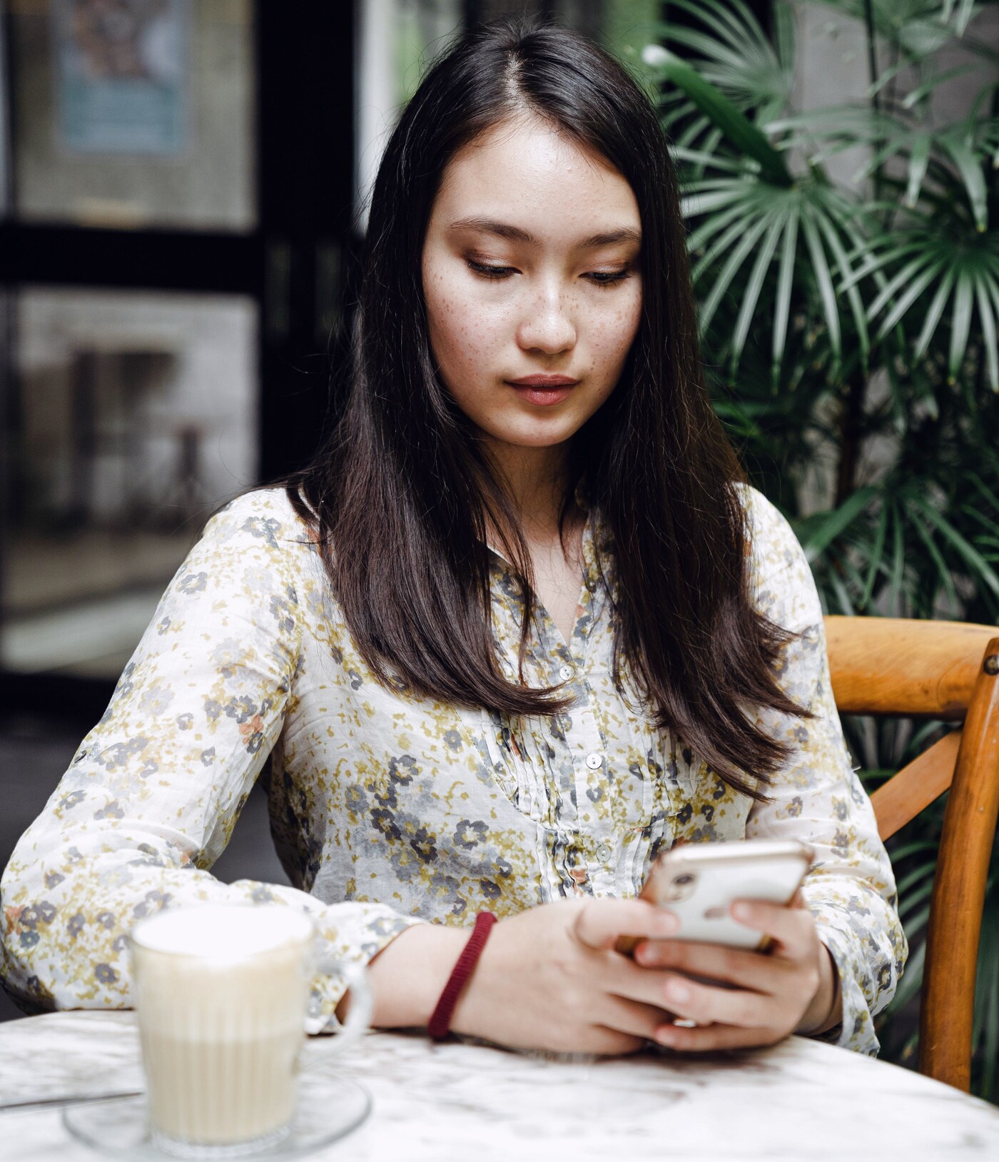 A woman reading a message on her phone at a cafe table