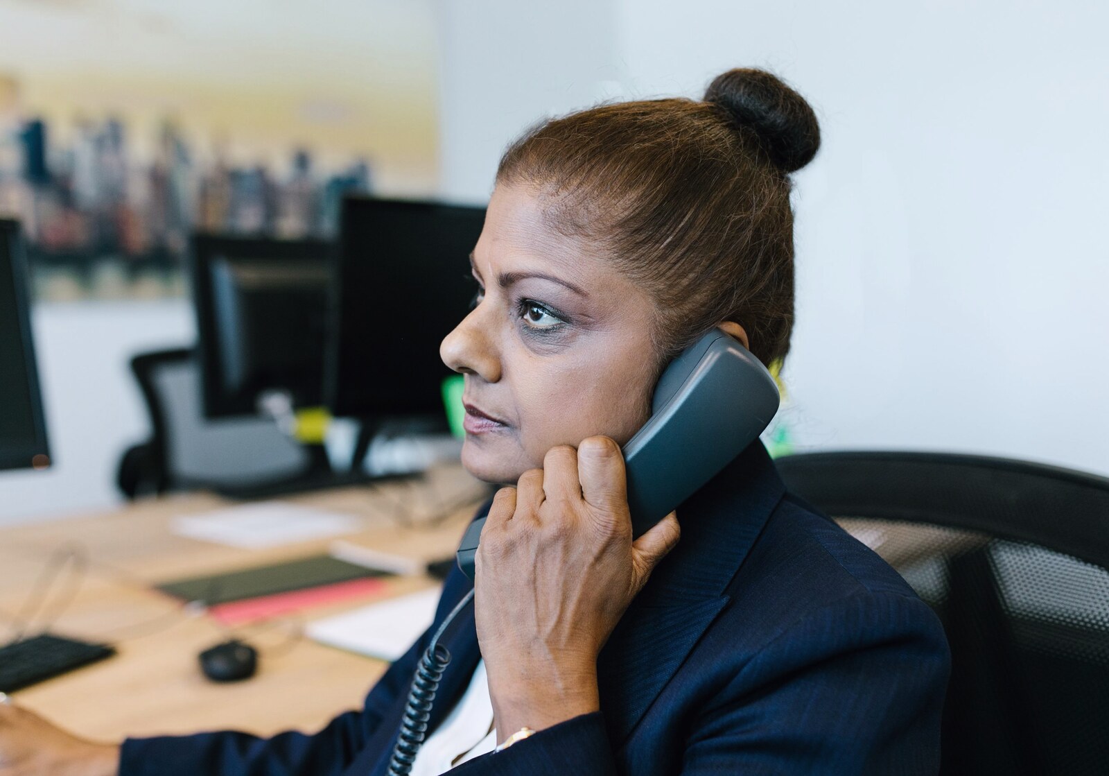 A woman taking a call on a desk phone in an office